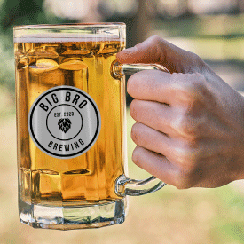 Hand holding beer stein with brewery sticker on it